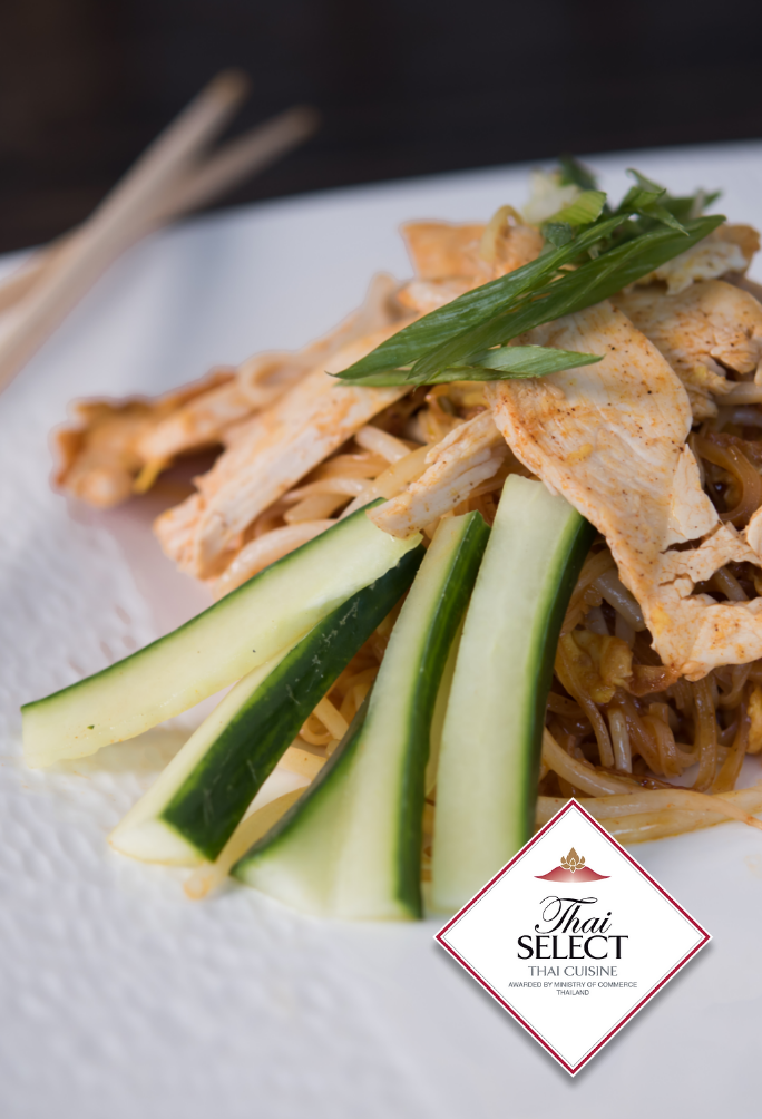 Overhead of a plate of Pad Thai pasta on a plate topped with cucumber ribbons and chicken with the Thia Select Logo.