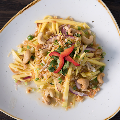 Overhead of plate with Yum Ma Muang (Thai Mango Salad) prepared with fine julienned green mango, red & green onion, coriander topped with crushed peanuts and spicy Thai dressing.