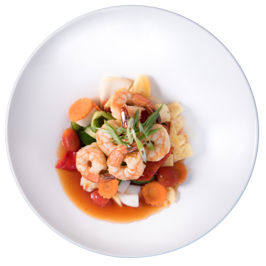 Overhead of a round, white plate with Pad Priew Wan (Sweet and Sour) prepared with pineapple, onion, cucumber, tomato and stir-fried in a tangy sauce topped with cooked shrimp.