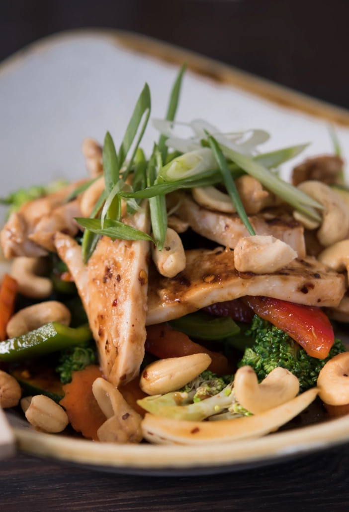 Up-close image of Chicken Pad Med Ma Muang (Cashew Nut) dish with sautéed carrots, onion, broccoli, and zucchini.